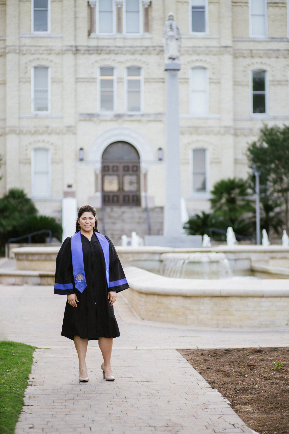 college senior standing by her university by San Antonio photographer