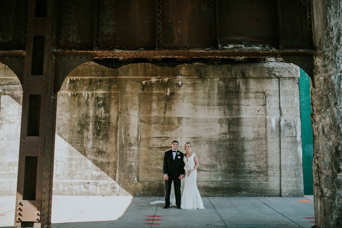 Couple stands under a bridge near Alexander Hotel Wedding