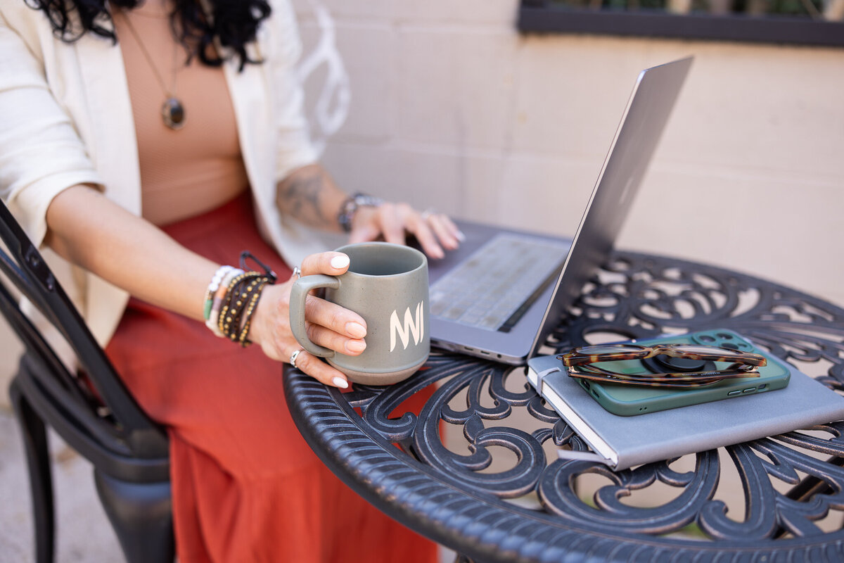 A-women-owned-business-owner-types-on-laptop-with-coffee-at-old-mill-cafe-for-brand-photos-in-baltimore-and-old-ellicott-city-maryland