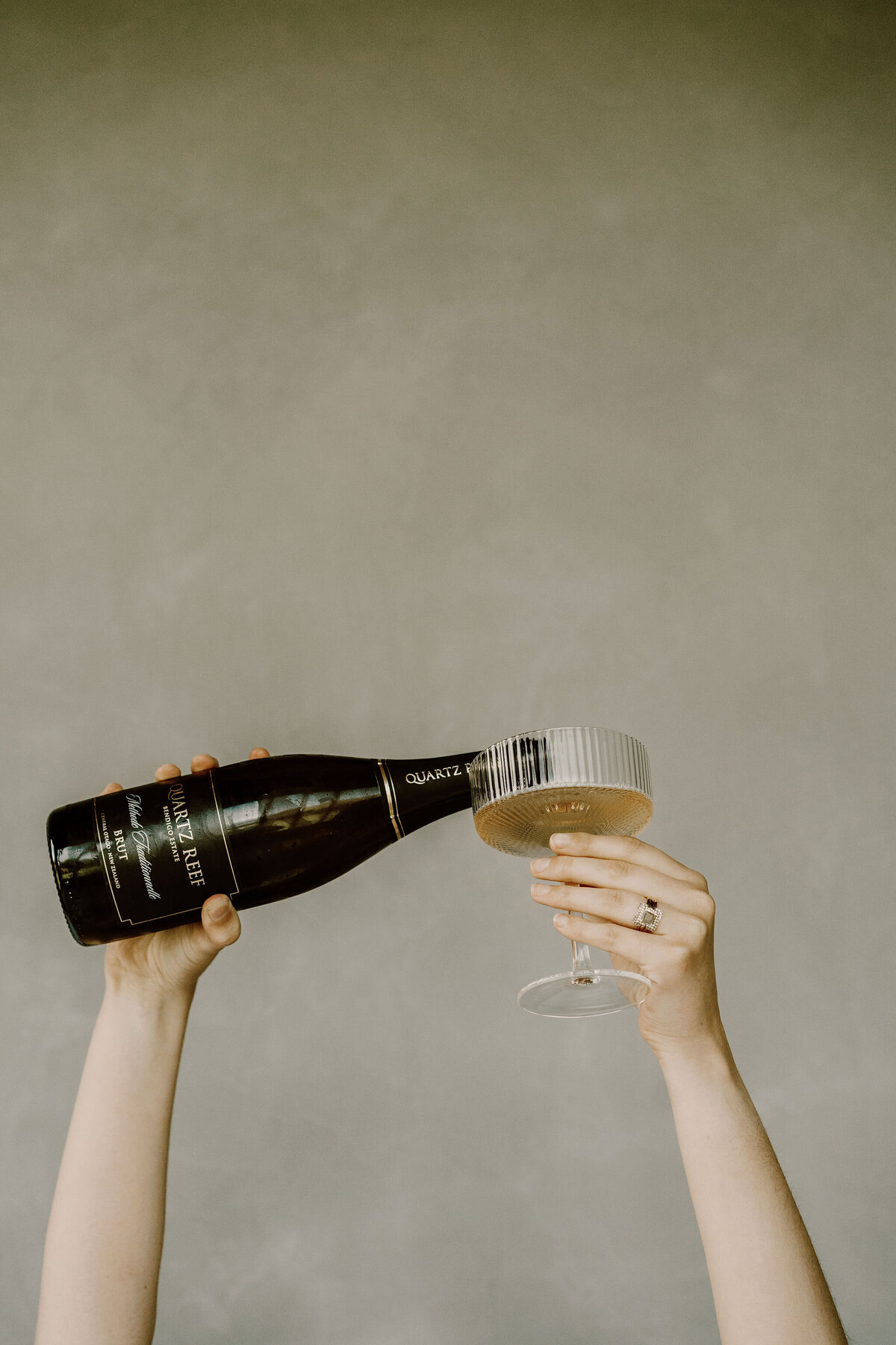 The Lovers Elopement Co - hands hold champagne glass and fill from bottle