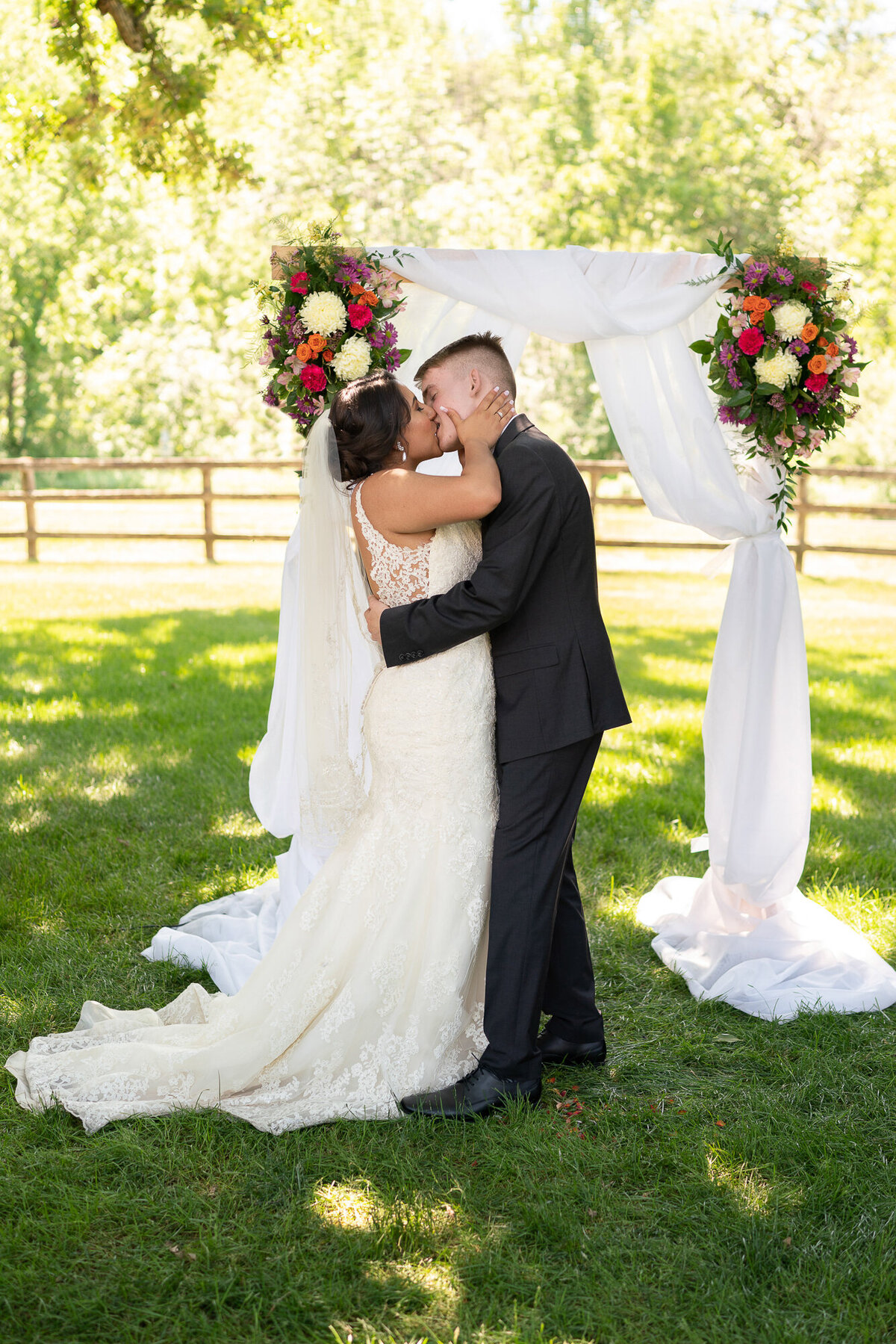 Bride and groom kiss during wedding ceremony at Mayowood Stone Barn.