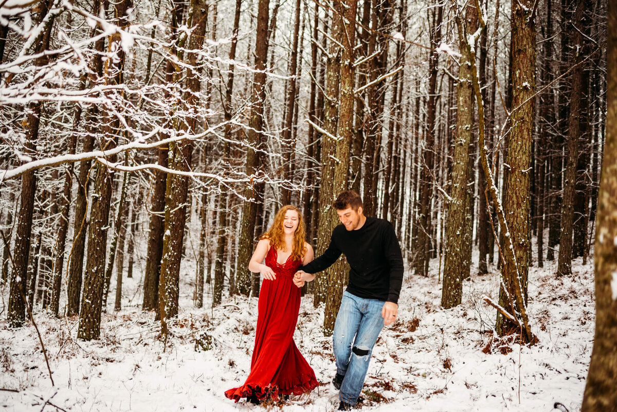 photo of a man and woman walking and laughing in a snowy forest