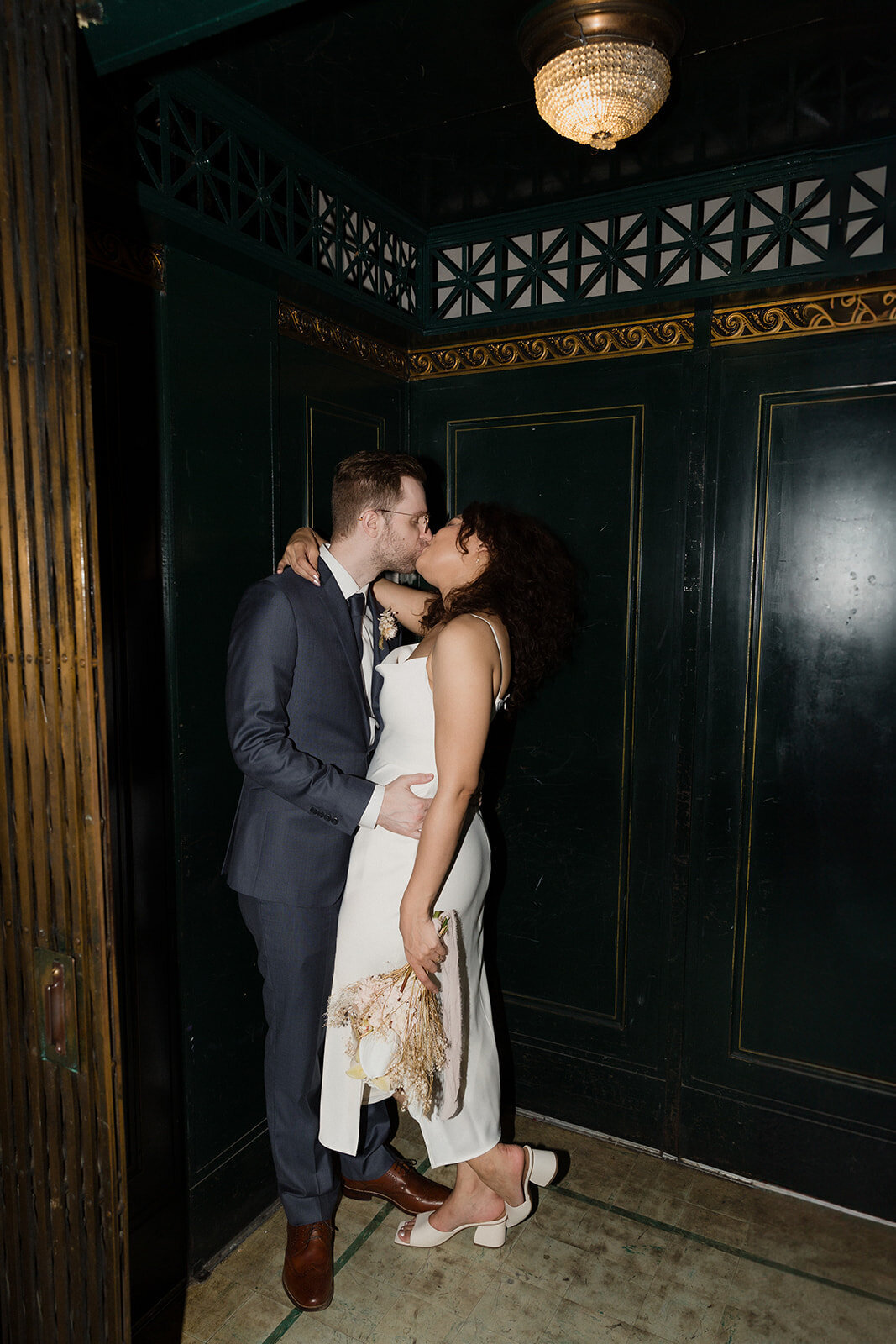 Just Married photo session couple kisses on dark old fashioned birdcage elevator at International Museum of Surgical Science.