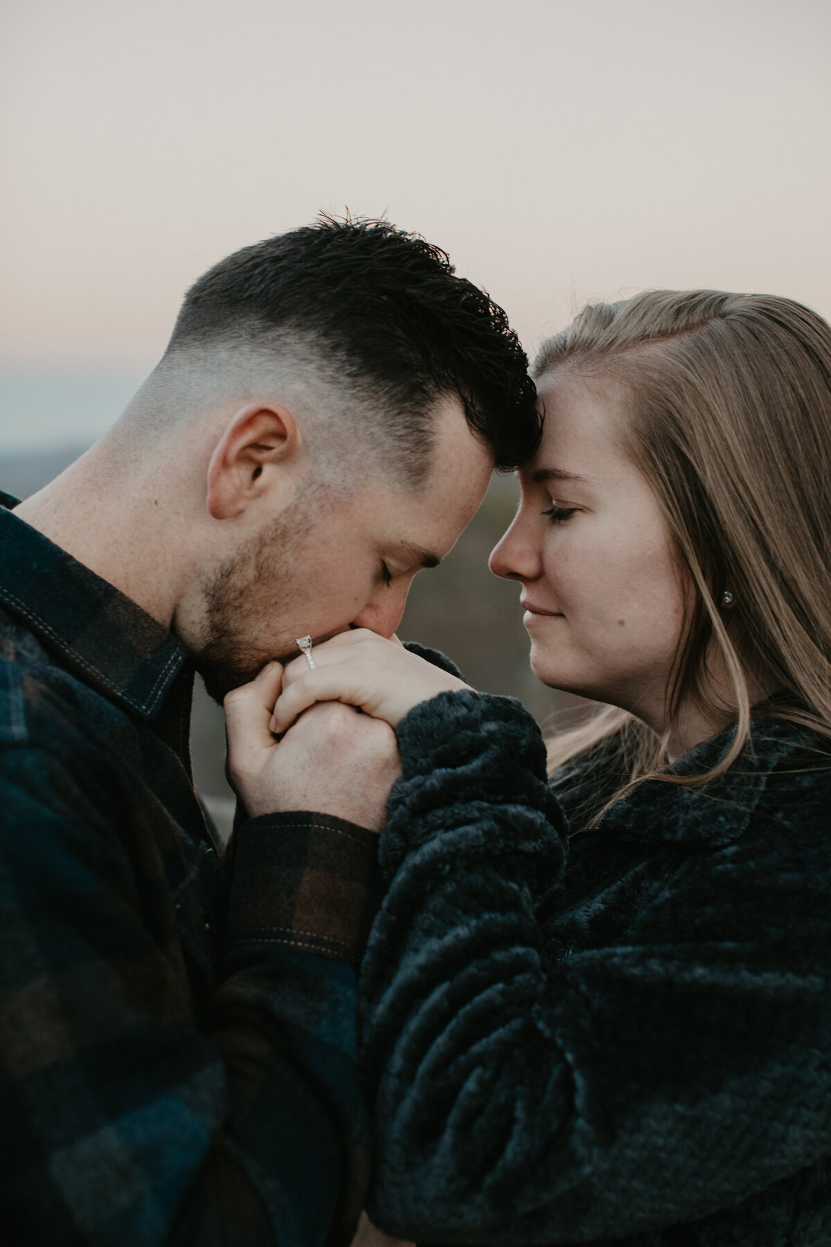 man kissing woman's hand with her ring on it