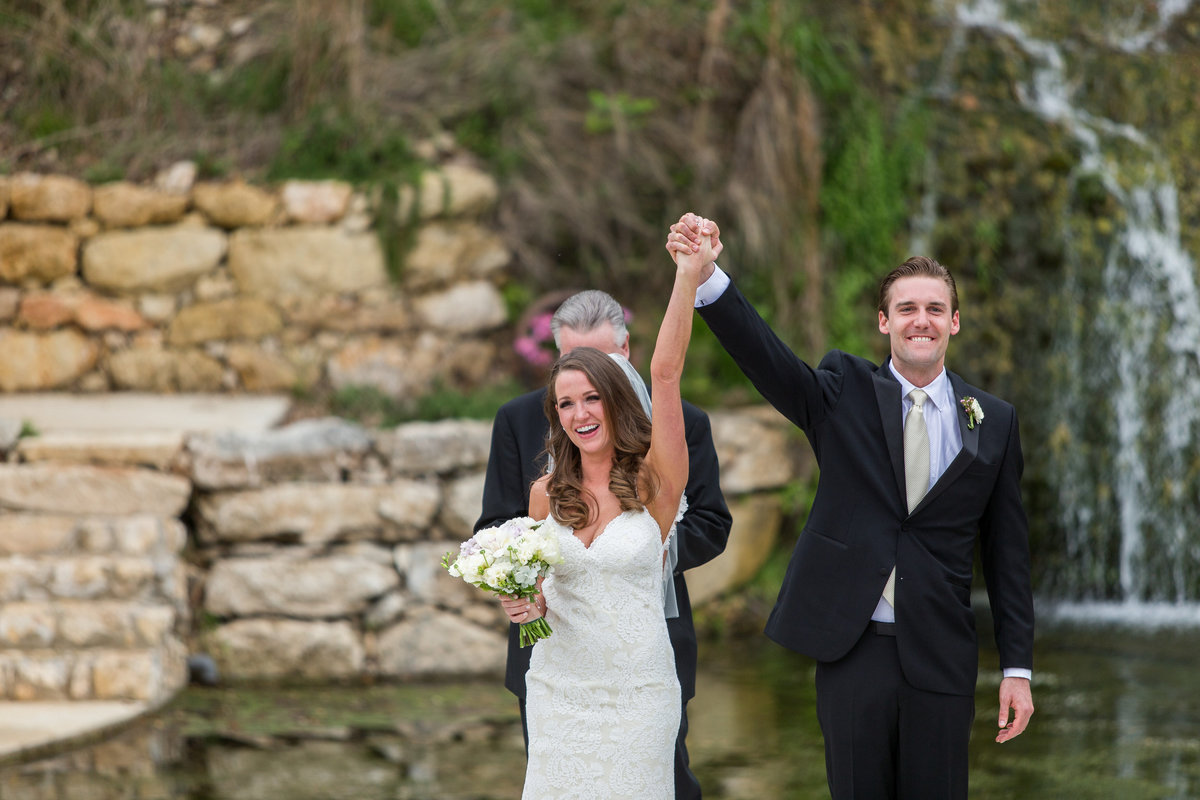 groom raising brides hand after ceremony with smiles on their face at Remi's Ridge at Hidden Falls wedding venue