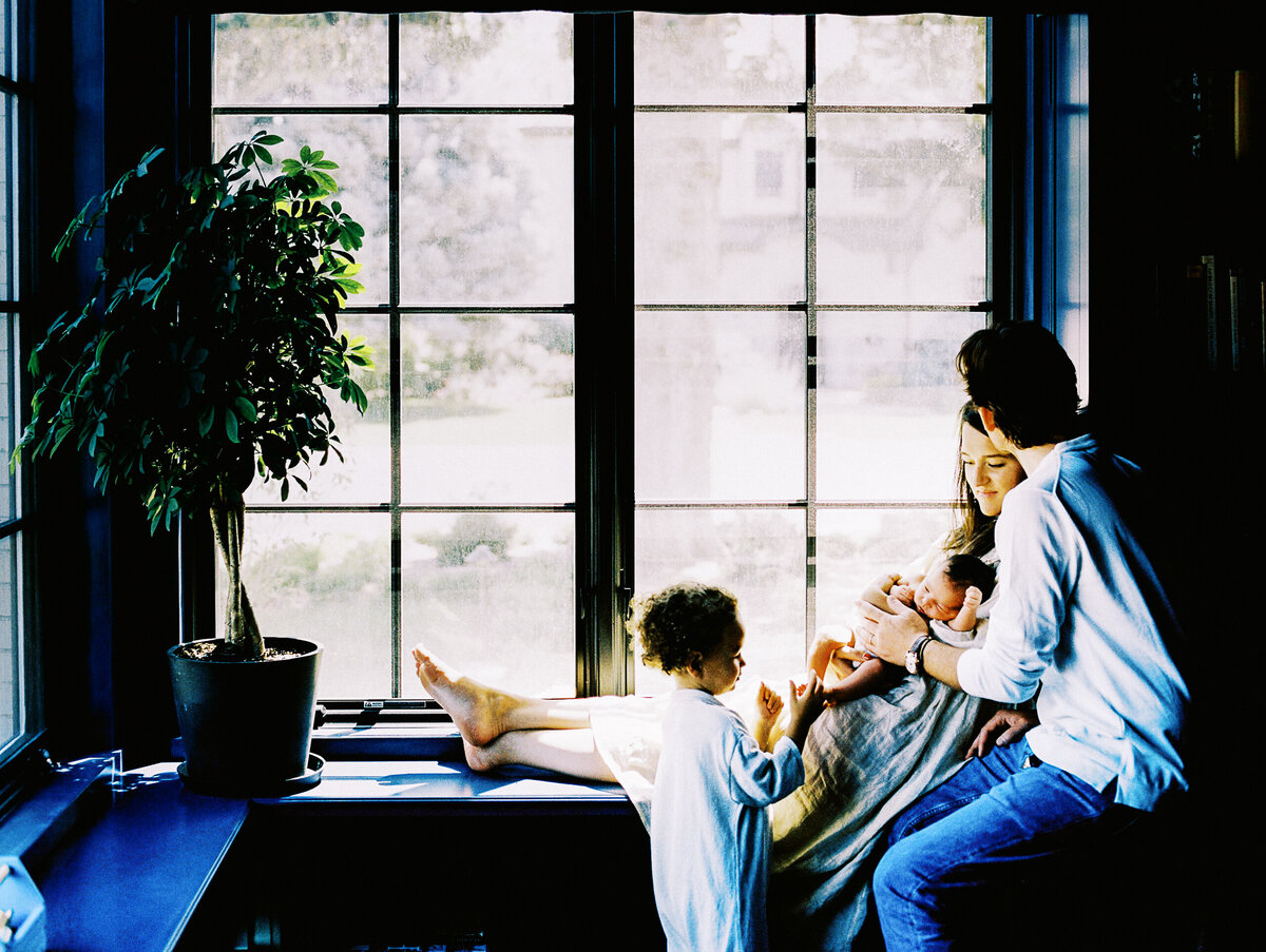 denver family sit in window during newborn photoshoot