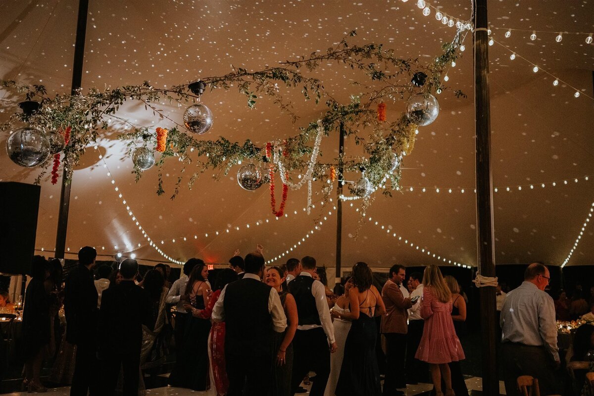 Tented wedding reception at night with disco balls and string lights