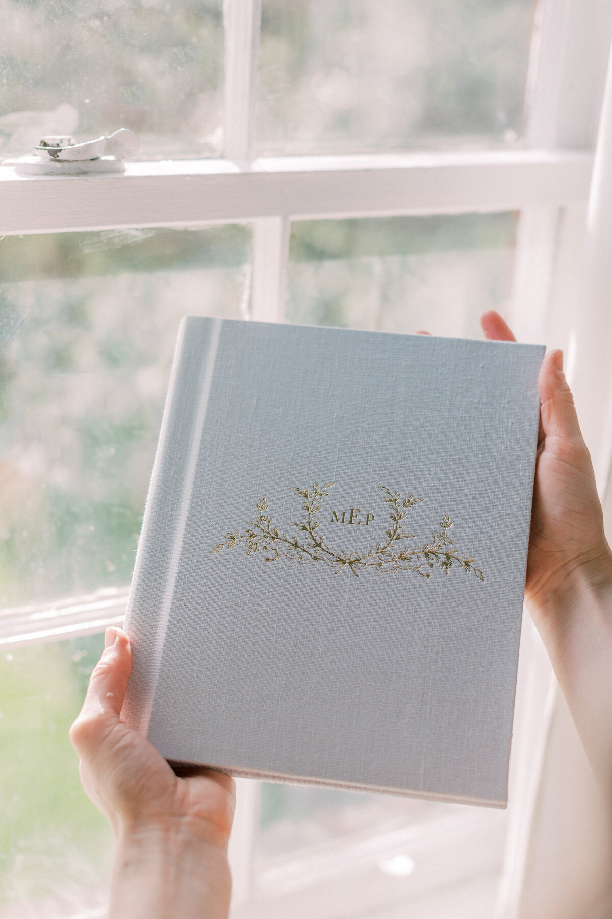 A light blue photo album with gold foil held by DC Photographer Marie Elizabeth Photography