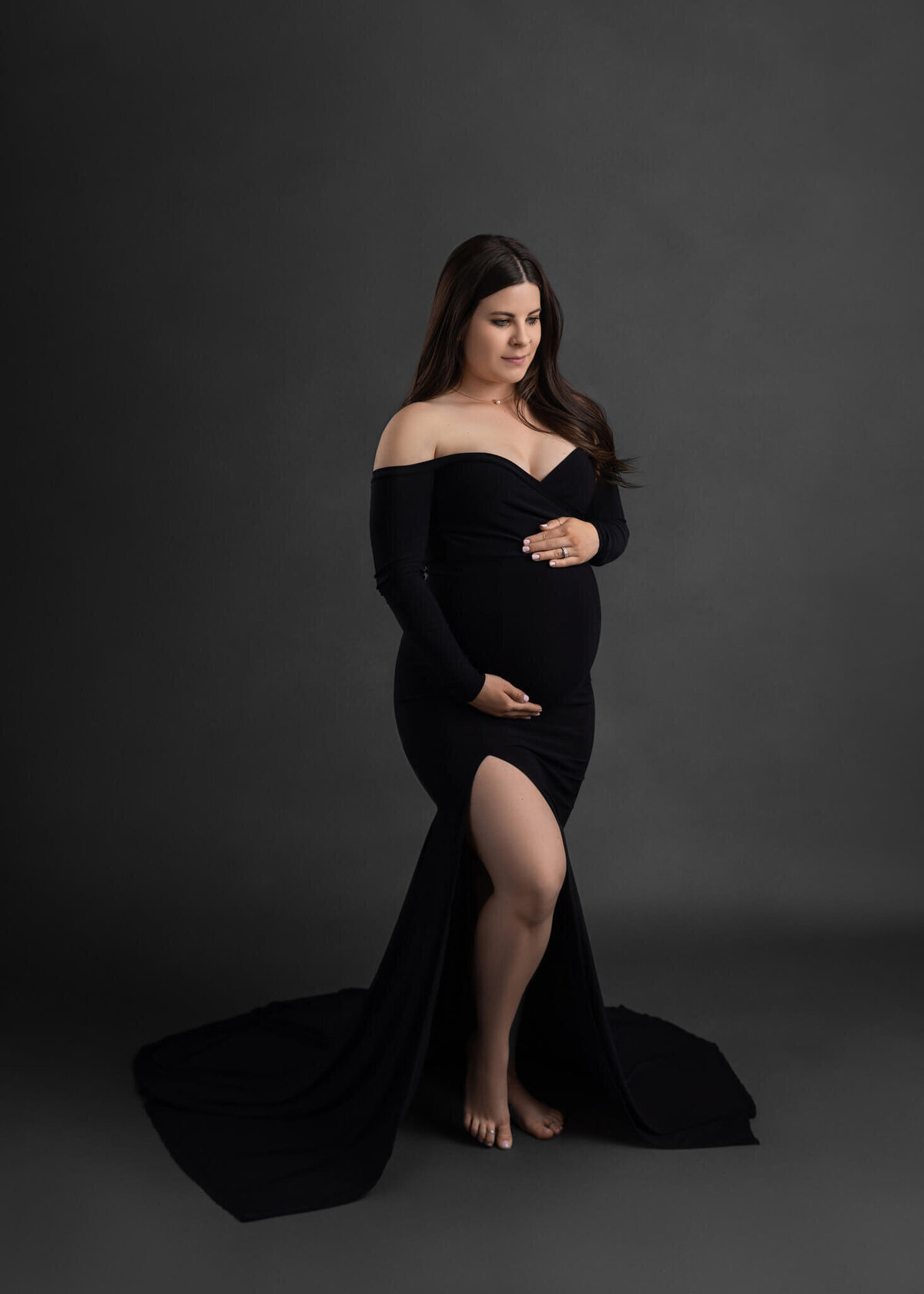 pregnant mom cradling her belly wearing a black dress