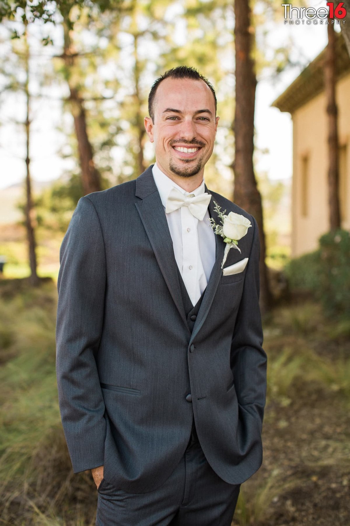 Groom posing with his hands in his pockets and big smile