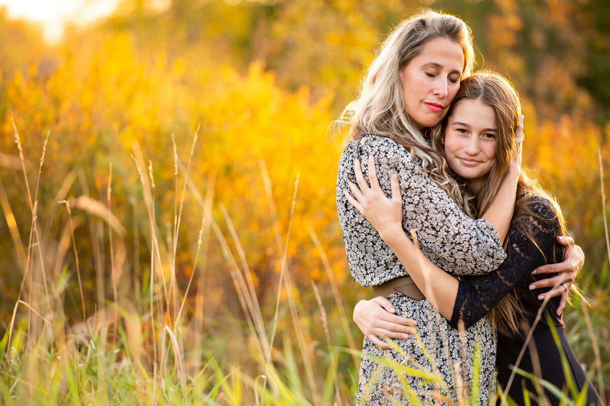 a mother hugs her young daughter at sunset golden hour taken by Ottawa family photographer JEMMAN Photography