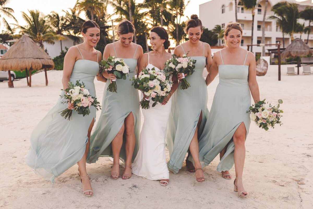 Bridesmaids walking on beach and laughing at wedding in Riviera Maya