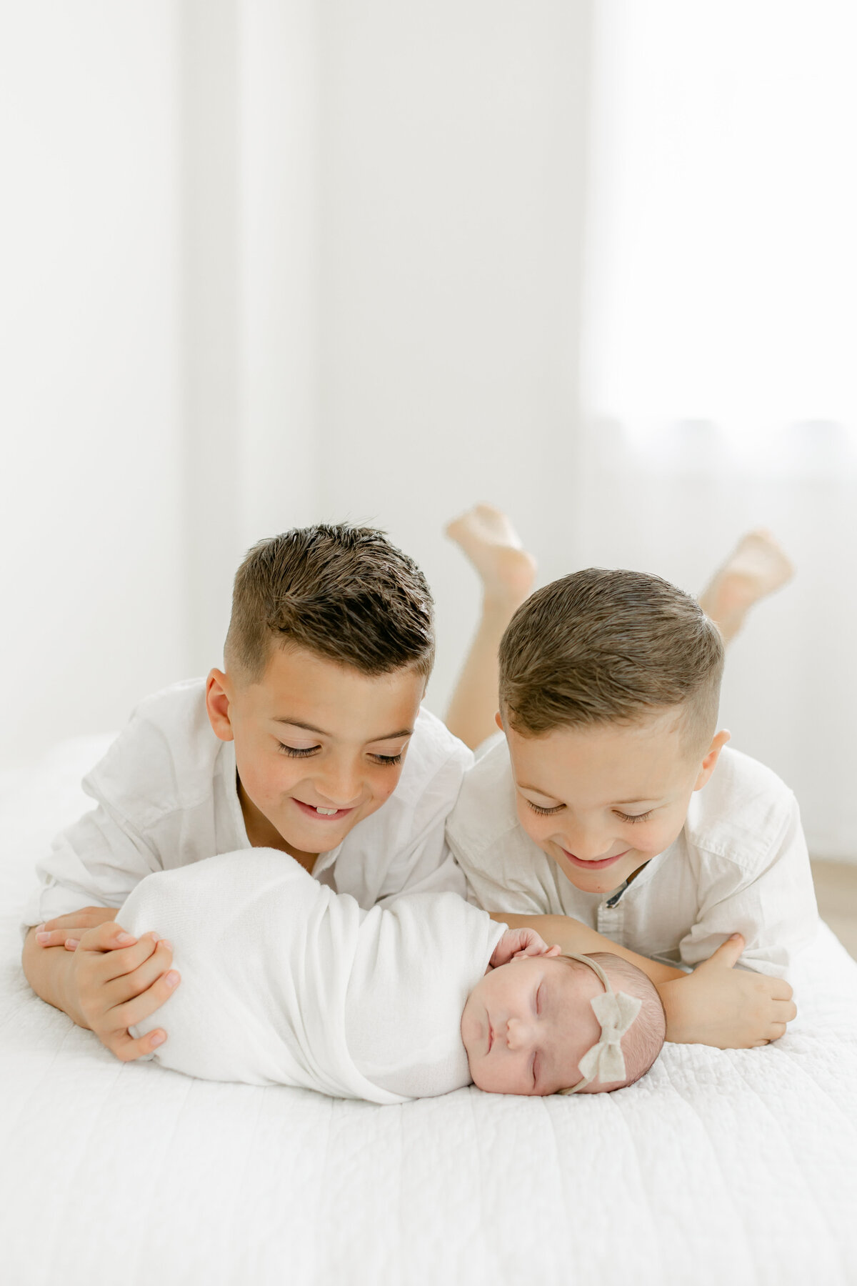 two big brothers adore their newborn baby sister while being photographed by Philadelphia Newborn Photographer Tara Federico