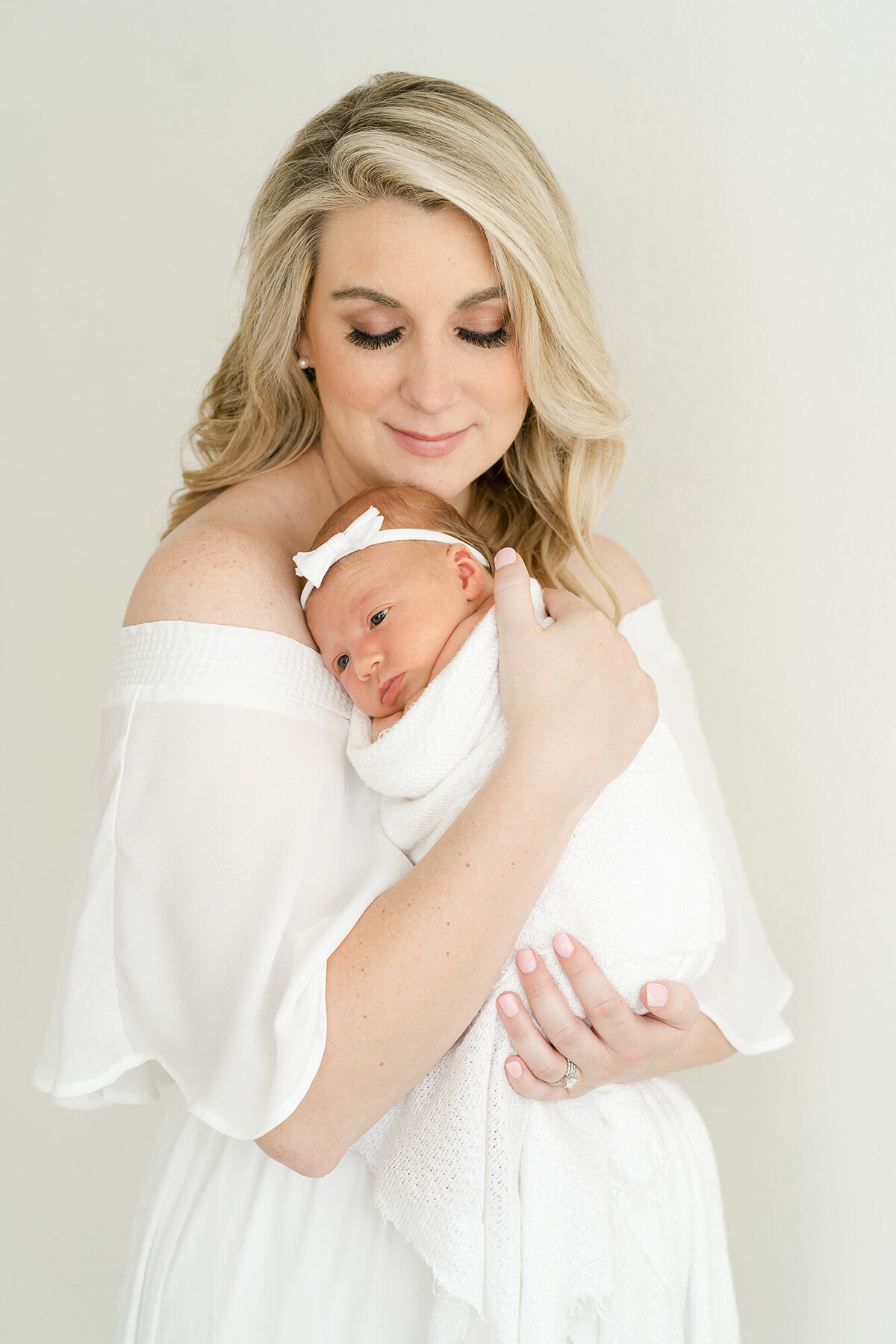 Newborn photo of mother in white dress holding baby girl at Julie Brock Photography Studio in Louisville KY