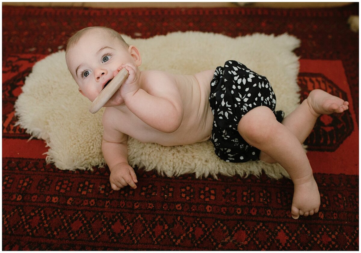 Baby lying on furry rug with teething ring in mouth  at sweet home family session in Austin by Amber Vickey Photography
