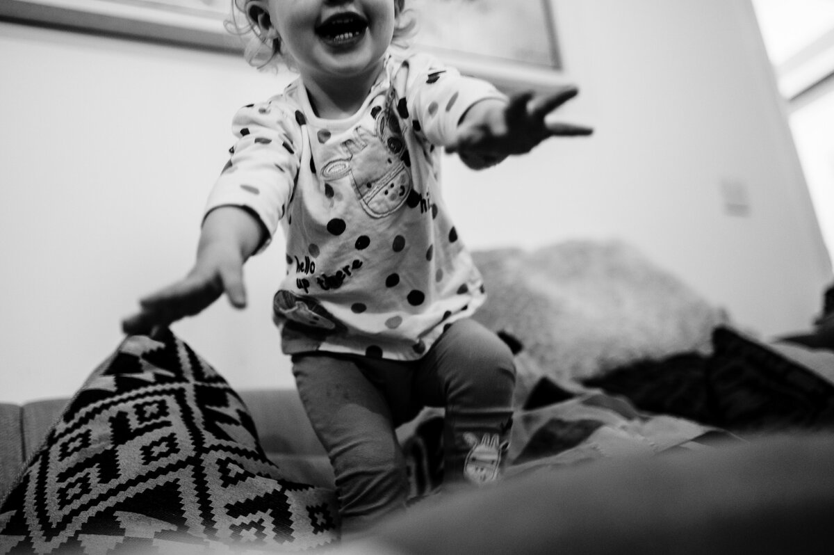 Little girl jumping off sofa at rutland family photoshoot at home