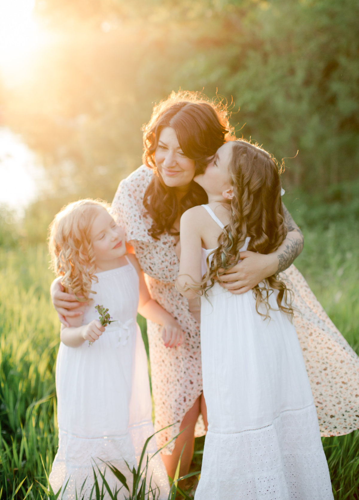 pregnant mom hugs her daughters in grass fields of summer lake rochester minnesota