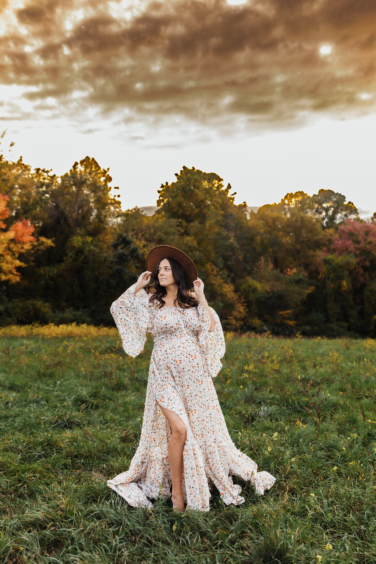 Radiant mother to be in a floral gown and boho hat during her Harrisburg maternity session