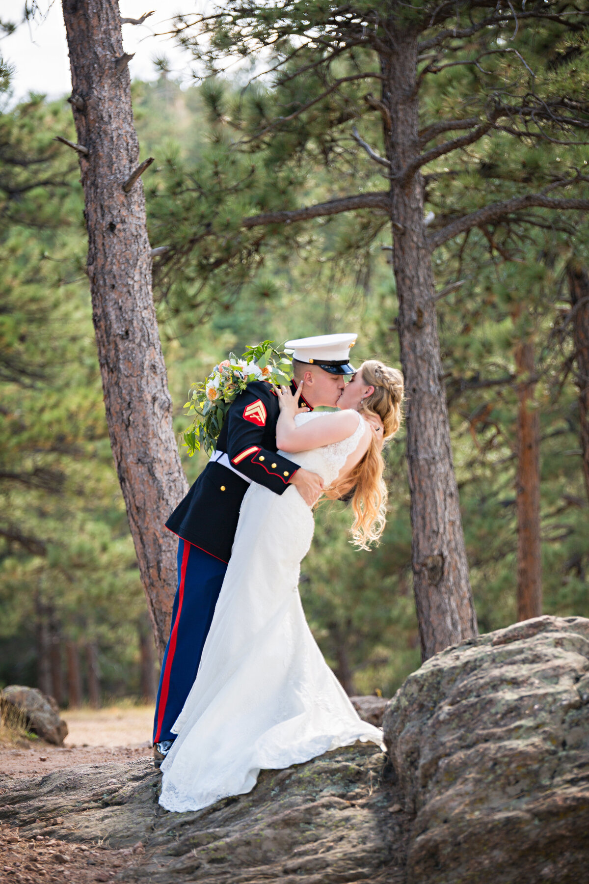 groom in uniform dips his bride in the woods