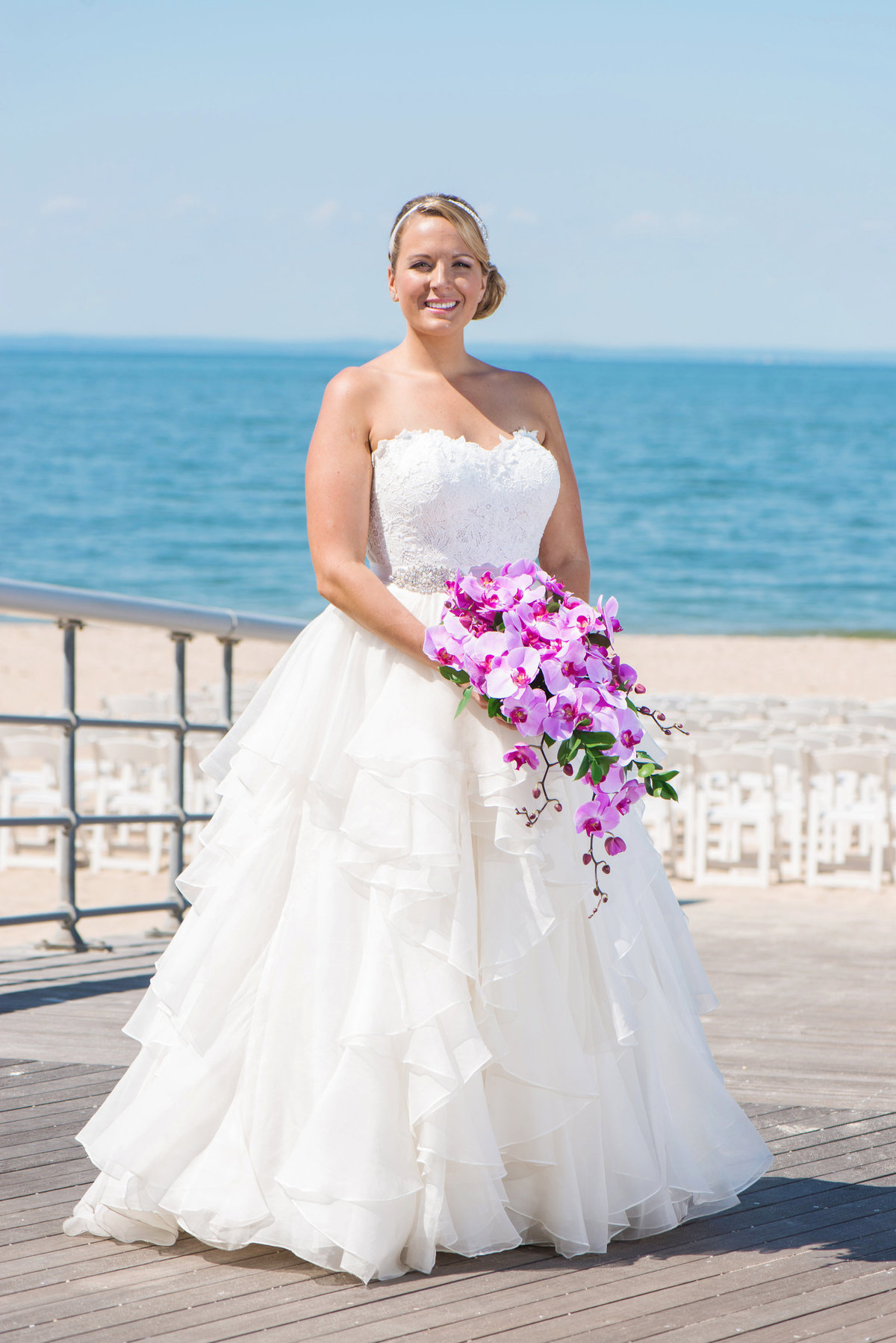 photo of bride holding bouquet on the boardwalk with beach view from wedding at Pavilion at Sunken Meadow