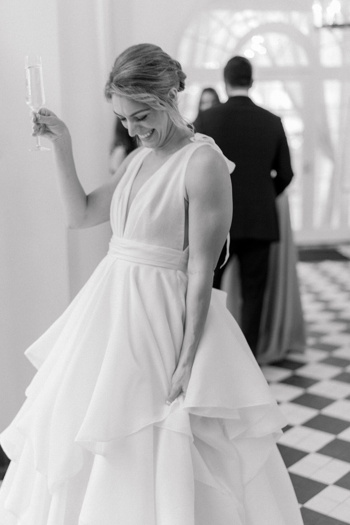 Candid photo of bride at Cocktail hour. Happy bride at Lowndes Grove spring wedding. Black and white Charleston wedding photographer. Kailee DiMeglio Photography.