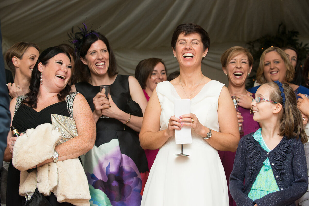 Bride and her friends listening to speeches and laughing