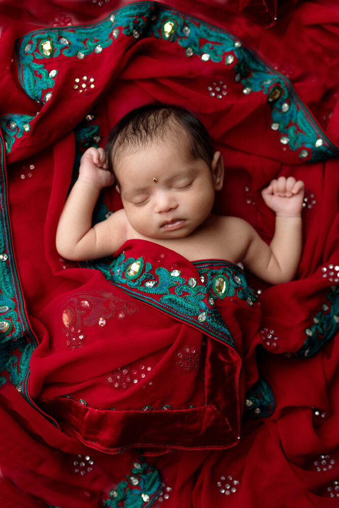 Newborn session of baby girl in red and green blanket