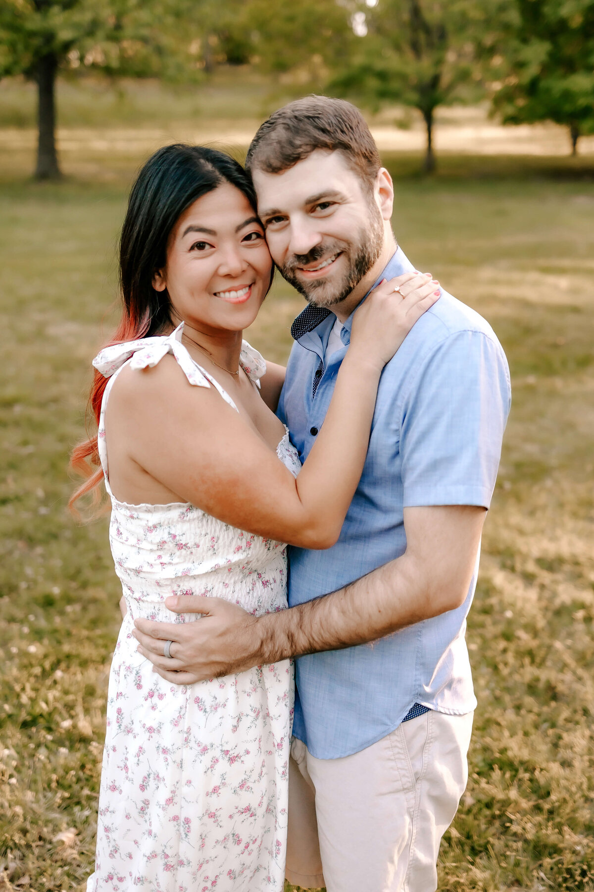 A married couple stand with their bodies pressed against each other and faces cheek to cheek while they smilr for the  photographer.