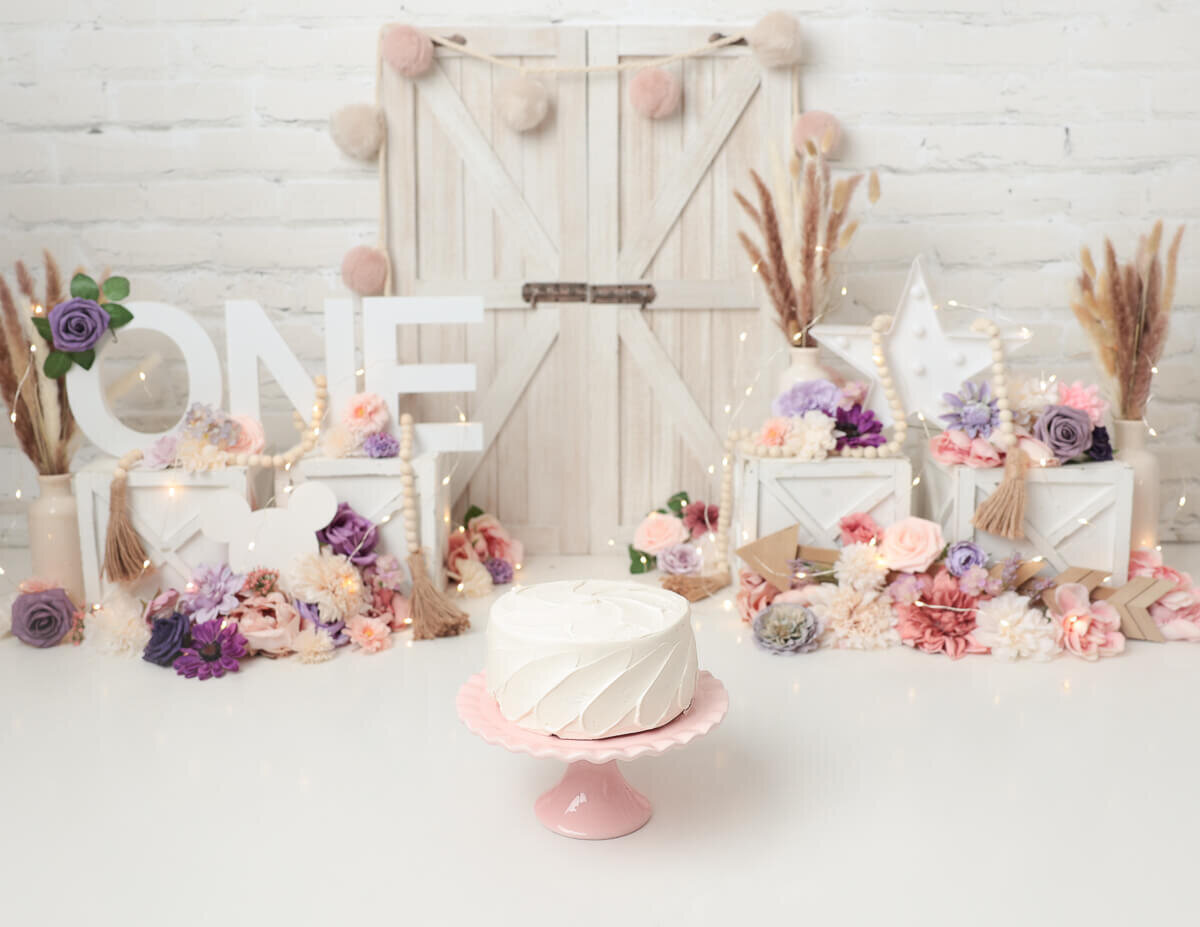 Beautifully styled boho cake smash scene with a decorated cake and playful props in Rochester, NY.