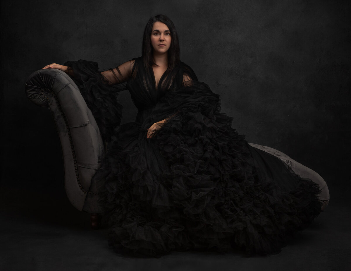 A woman with dark hair wearing a black ruffled gown poses for a beauty portrait photograph at Janel Lee Photography studios in Cincinnati Ohio