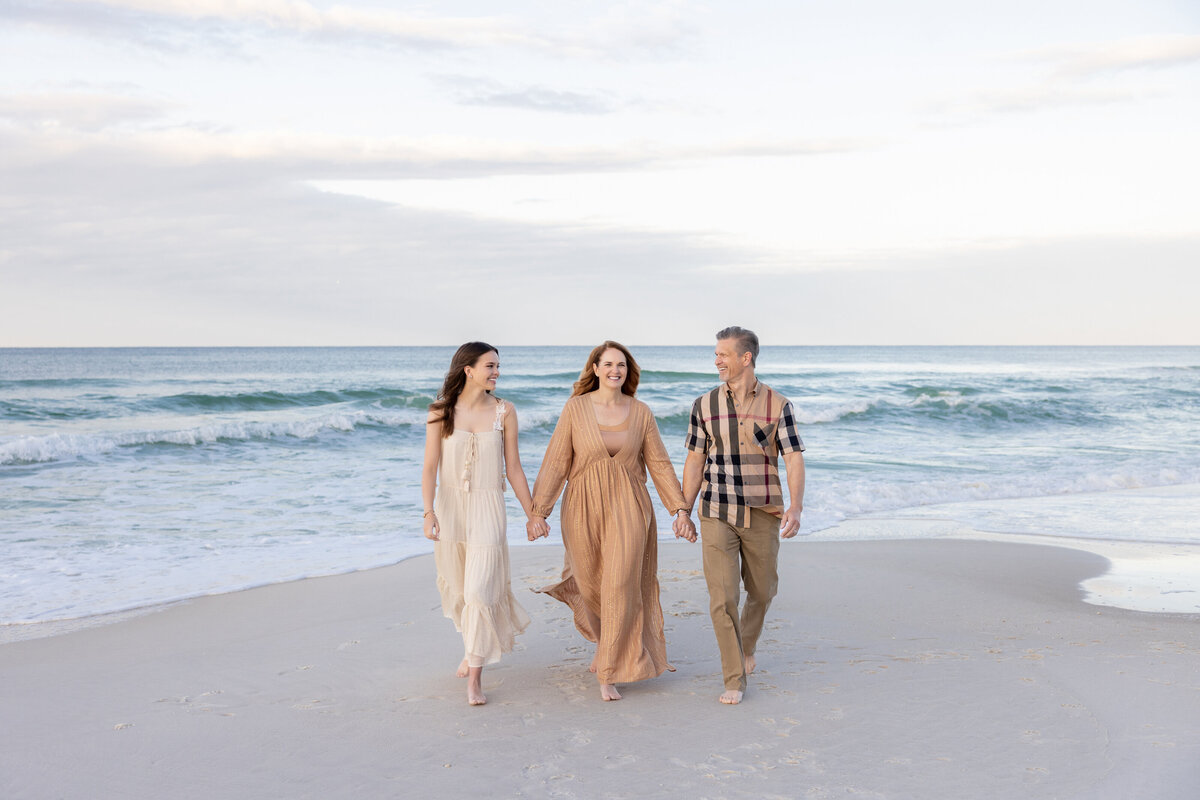 Three people holding hands and walking at the beach