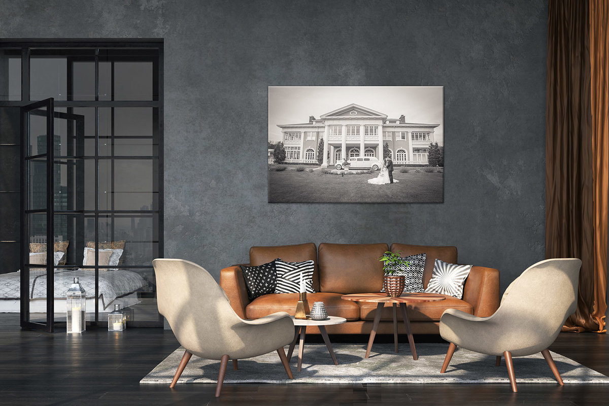 Large fine-art print in a living room with brown leather sofa and glass door.