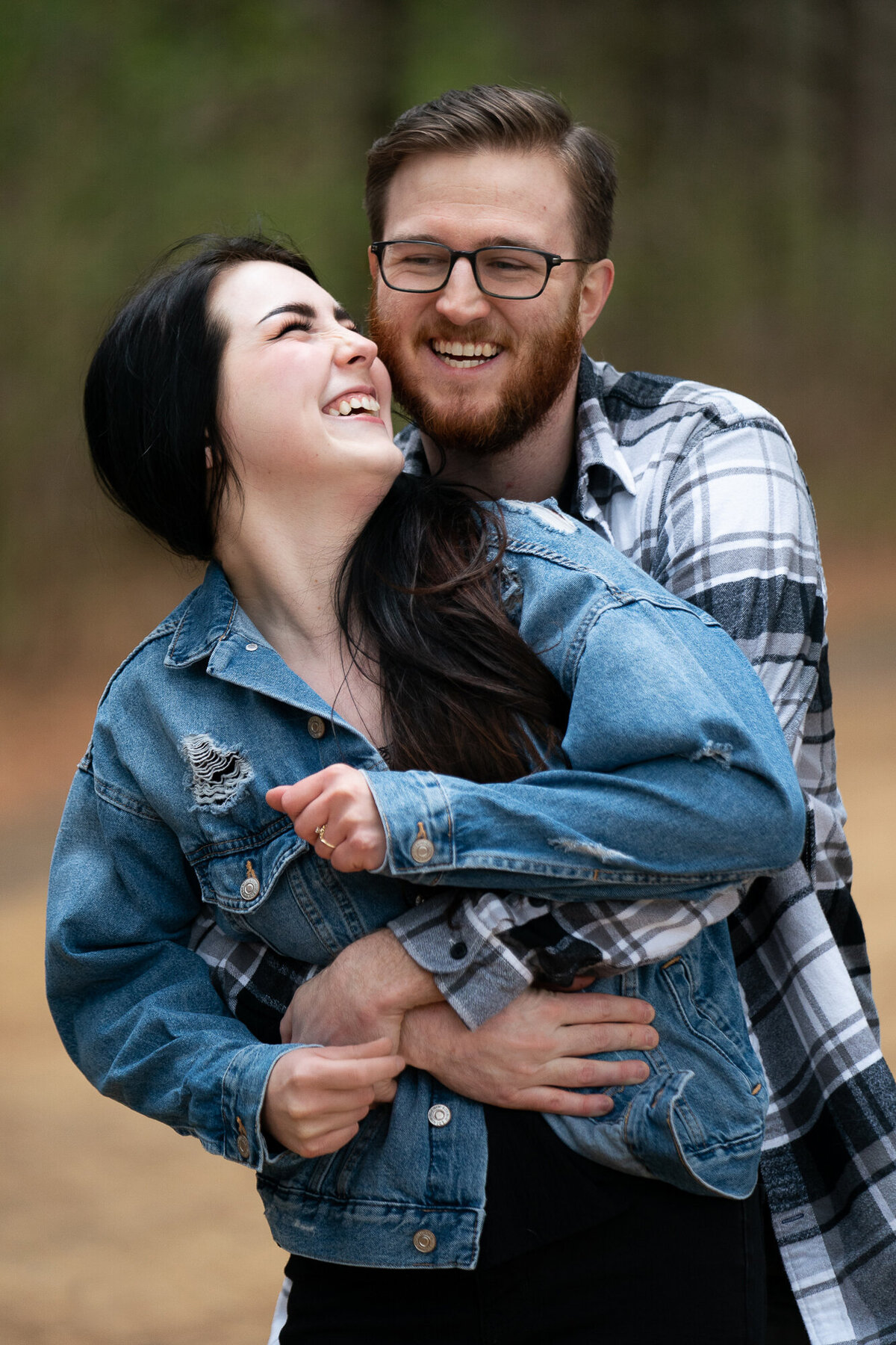 Man in flannel and woman in denim jacket snuggle and laugh.