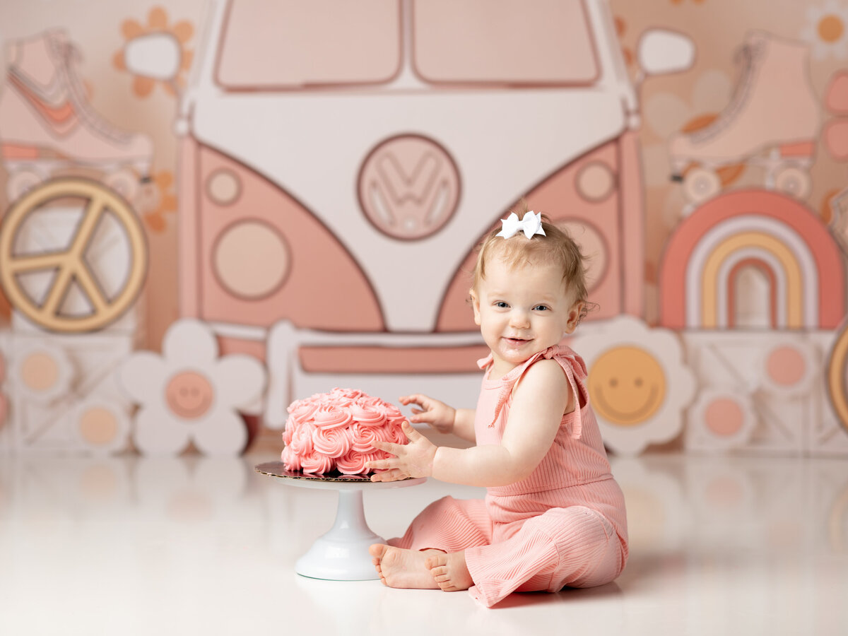 one year old girl in pink jumper sitting for groovy themed cake smash cleveland family photographer