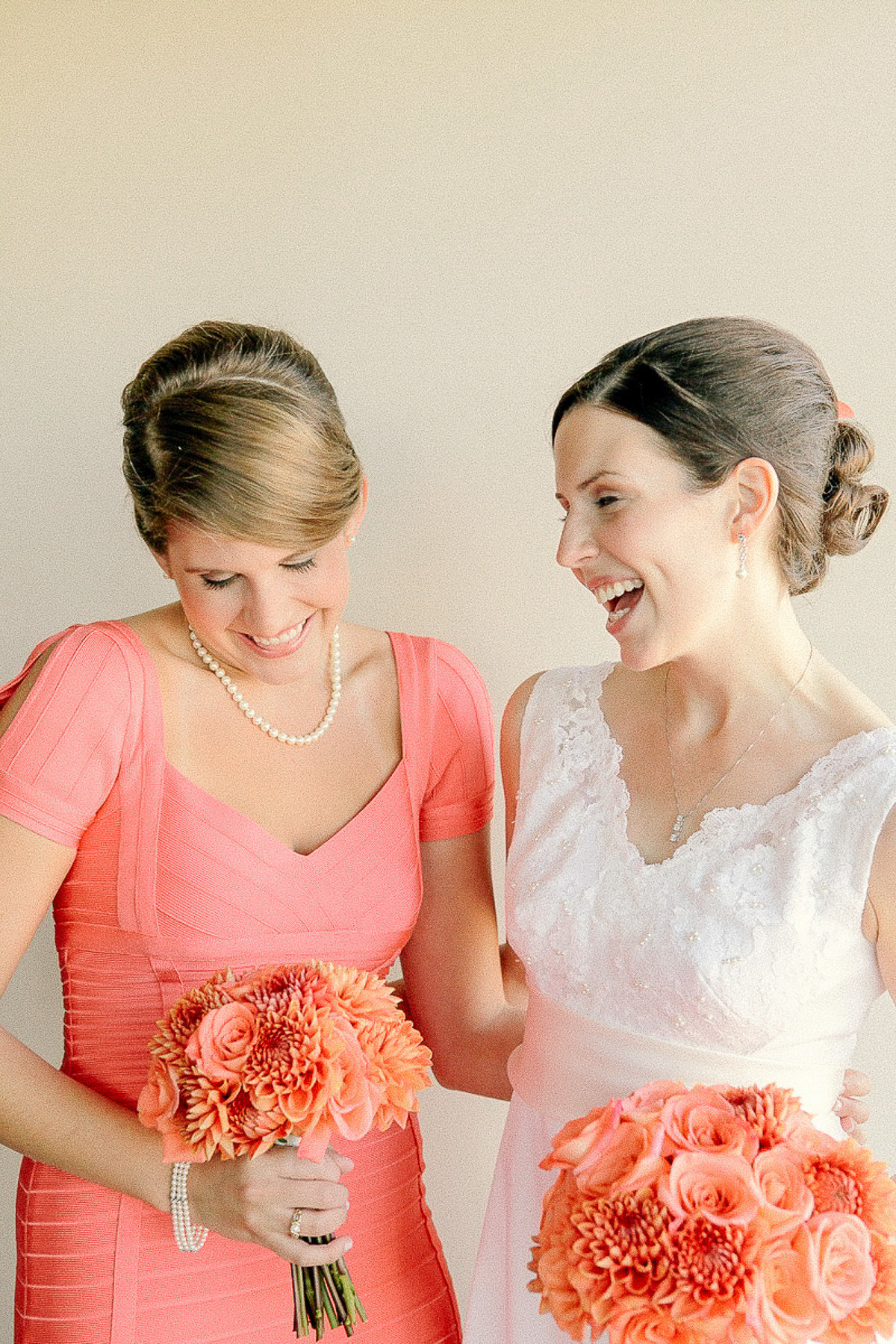 Bride with maid of honor holding peach and orange bouquets