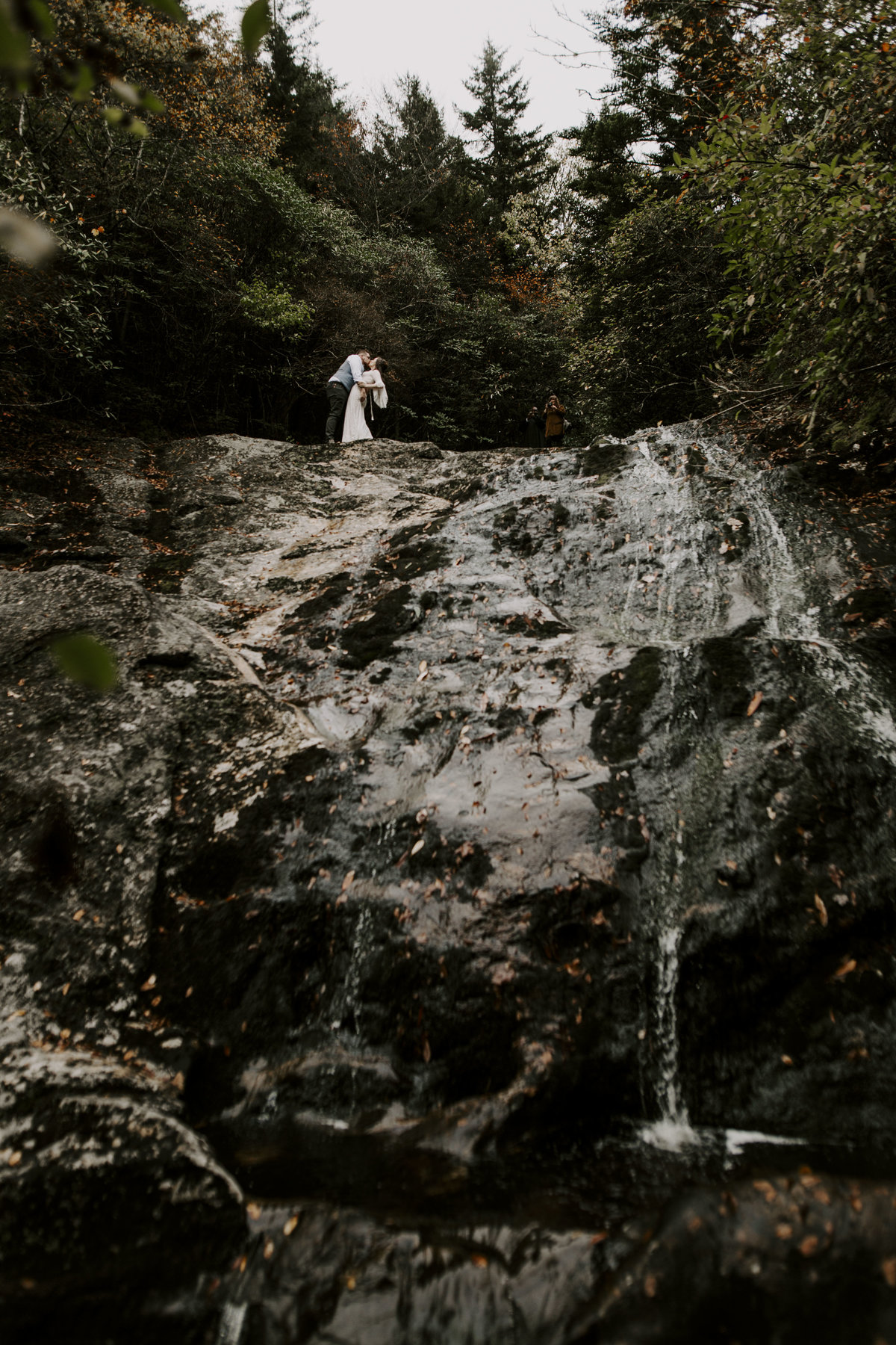 Newlywed couple hugging on top of a waterfall in Pisgah National Forest near Asheville North Carolina