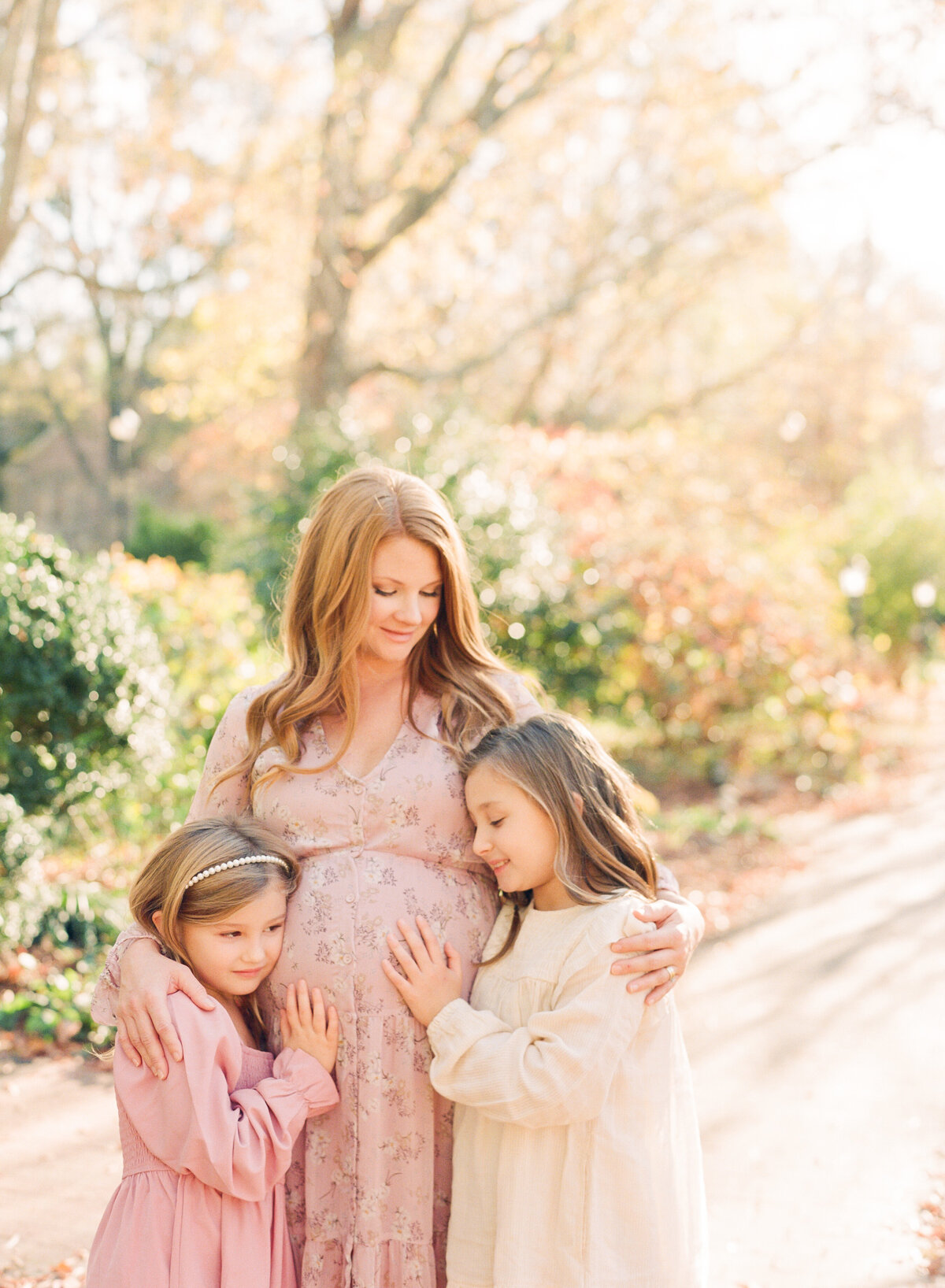 Mom snuggling daughters during a wake forest nc maternity session. Photographed by Raleigh maternity photograph A.J. Dunlap Photography.