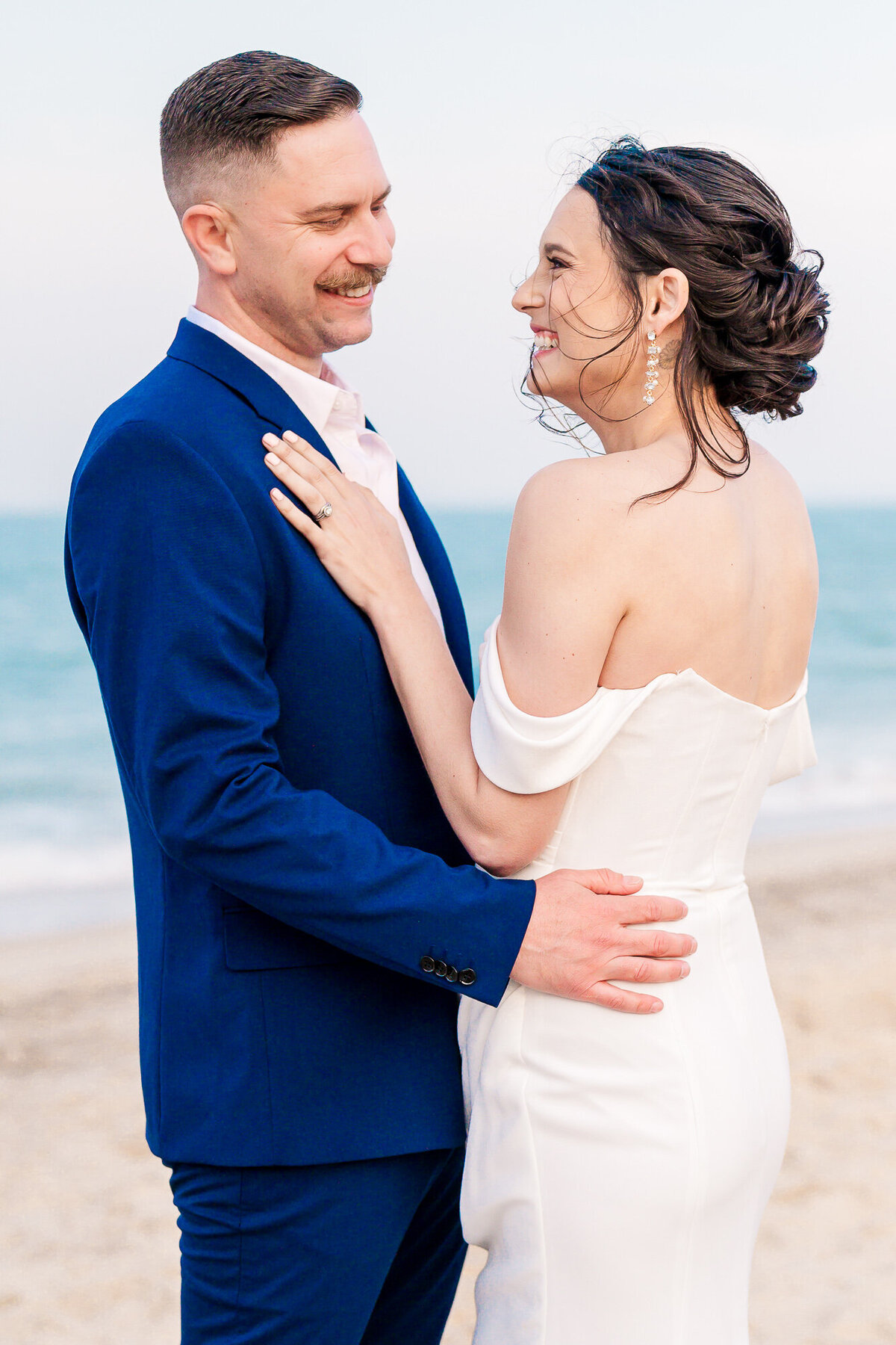A couple laughing on the beach during their destination wedding in North Carolina by JoLynn Photography, a North Carolina wedding photographer