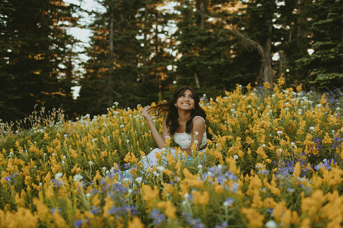 girl sitting in field of yellow wildflowers