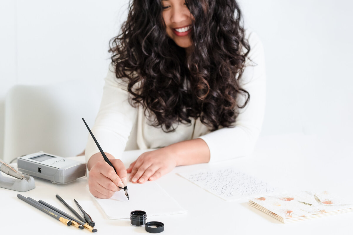 brand photo of a calligrapher doing her craft with pen and ink