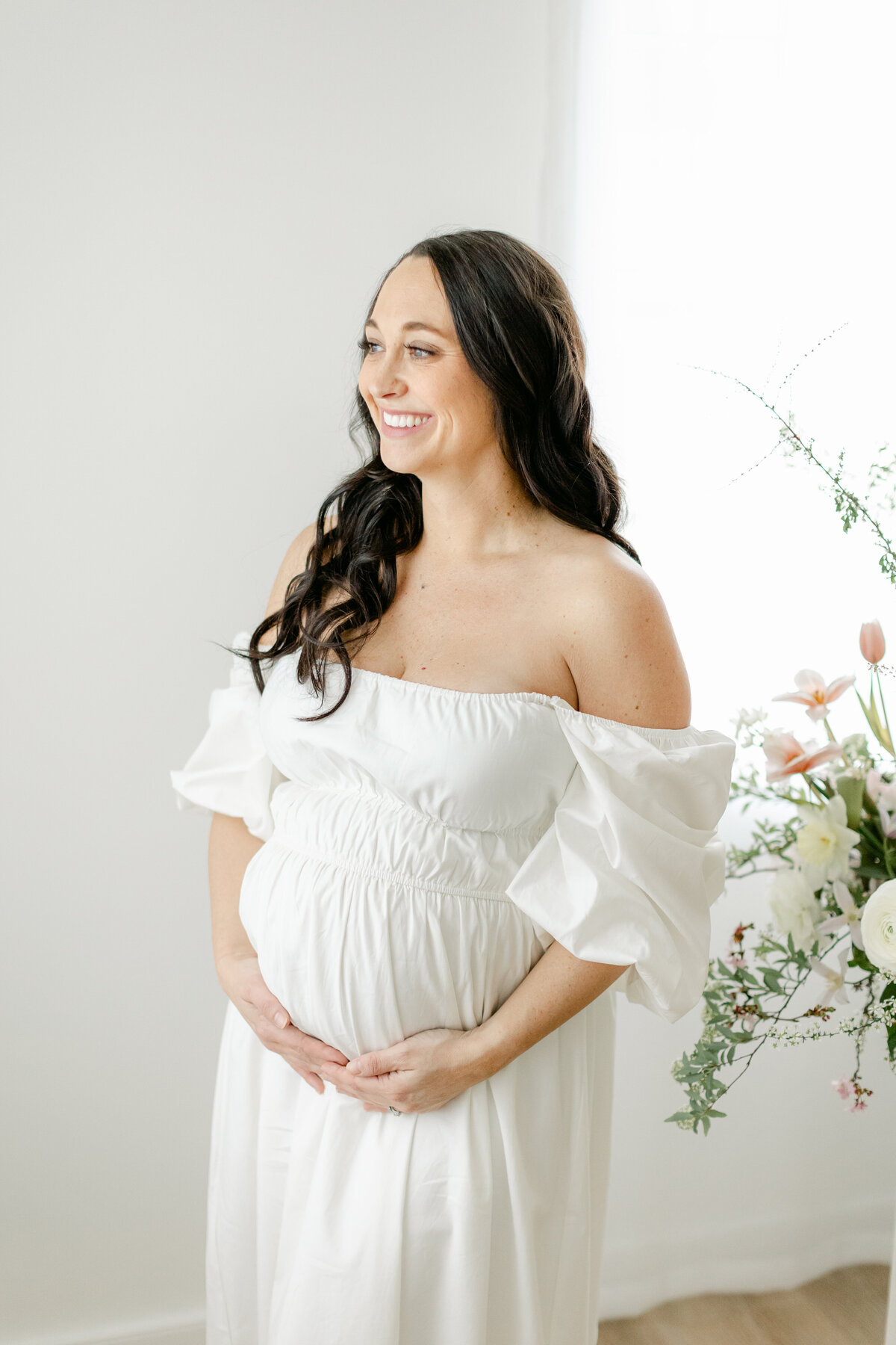 beautiful pregnant mom standing next to a floral installation photographed by Philadelphia Maternity Photographer