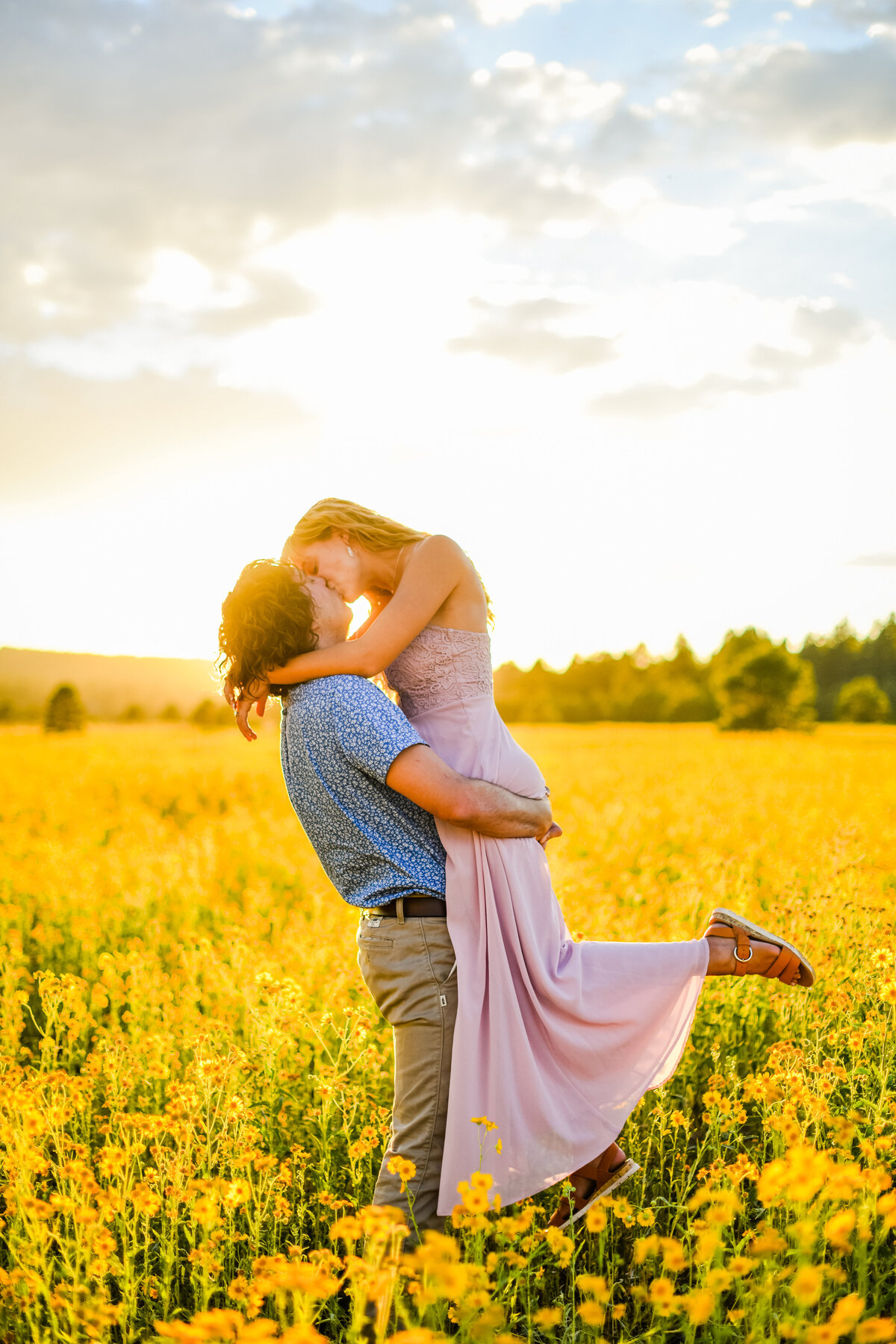 Couple engaged holding her up kissing sunset golden hour wildflowers yellow sunflowers Flagstaff Arizona
