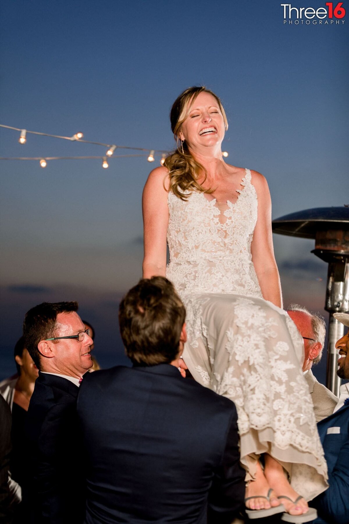 Groomsmen carry the Bride around as she sits atop a chair