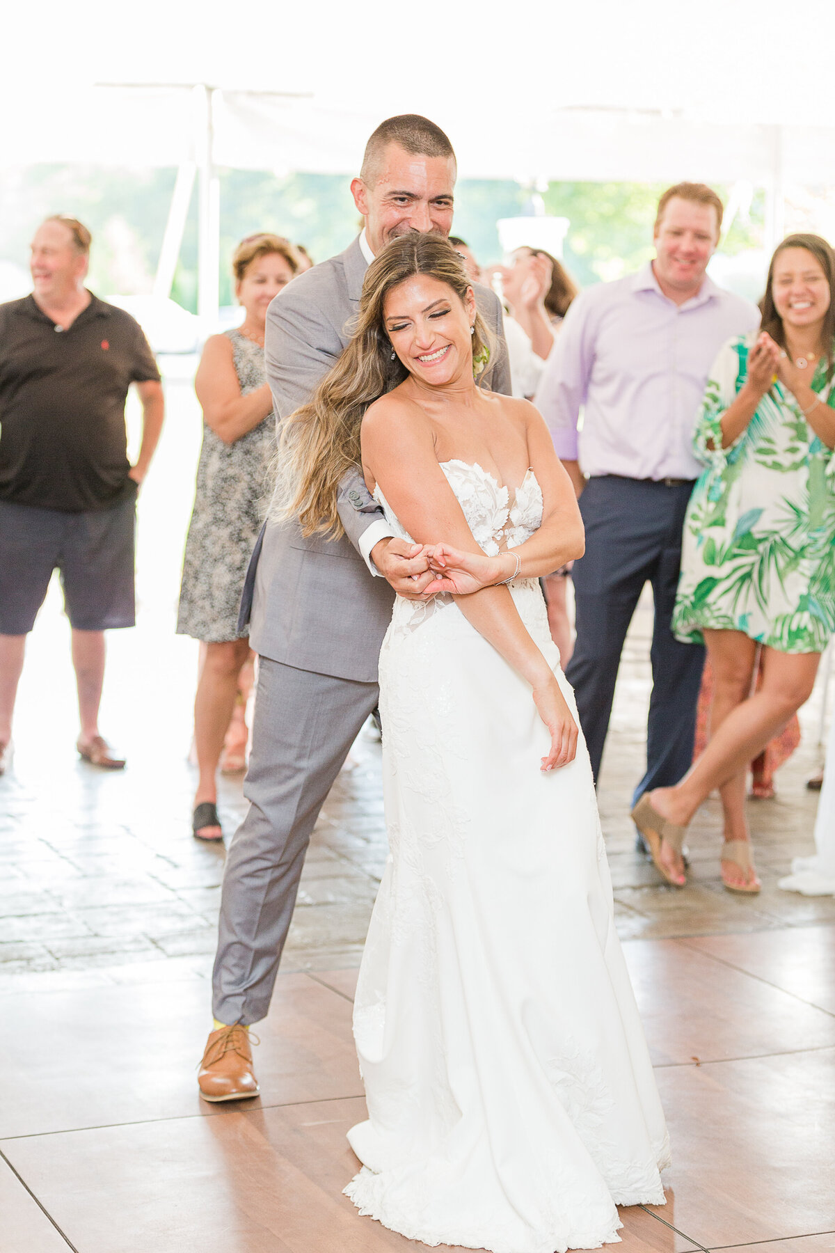 Bride and groom are laughing as they share their first dance at their Five Bridge Inn Wedding Reception. Guests are smiling and laughing in the background. Captured by best Massachusetts wedding photographer Lia Rose Weddings.