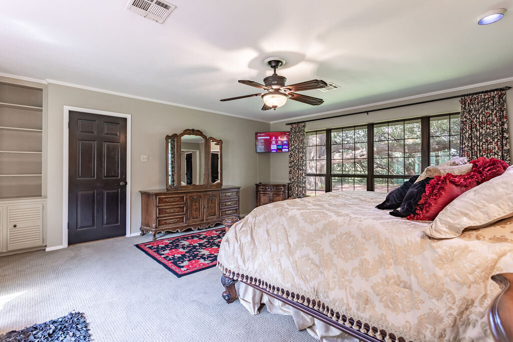Master bedroom with comfortable bedding and TV in this 5-bedroom, 4-bathroom vacation rental house for 16+ guests with pool, free wifi, guesthouse and game room just 20 minutes away from downtown Waco, TX.