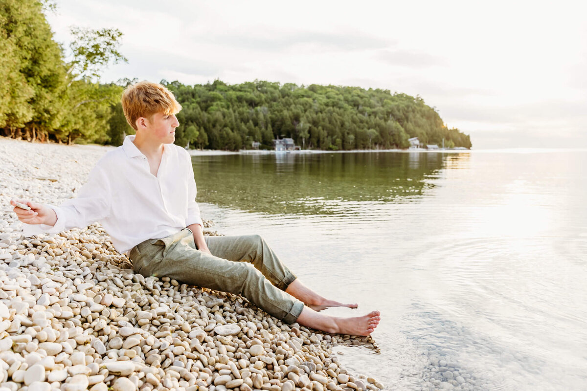 boy high schooler skipping stones during his Green Bay senior photography session