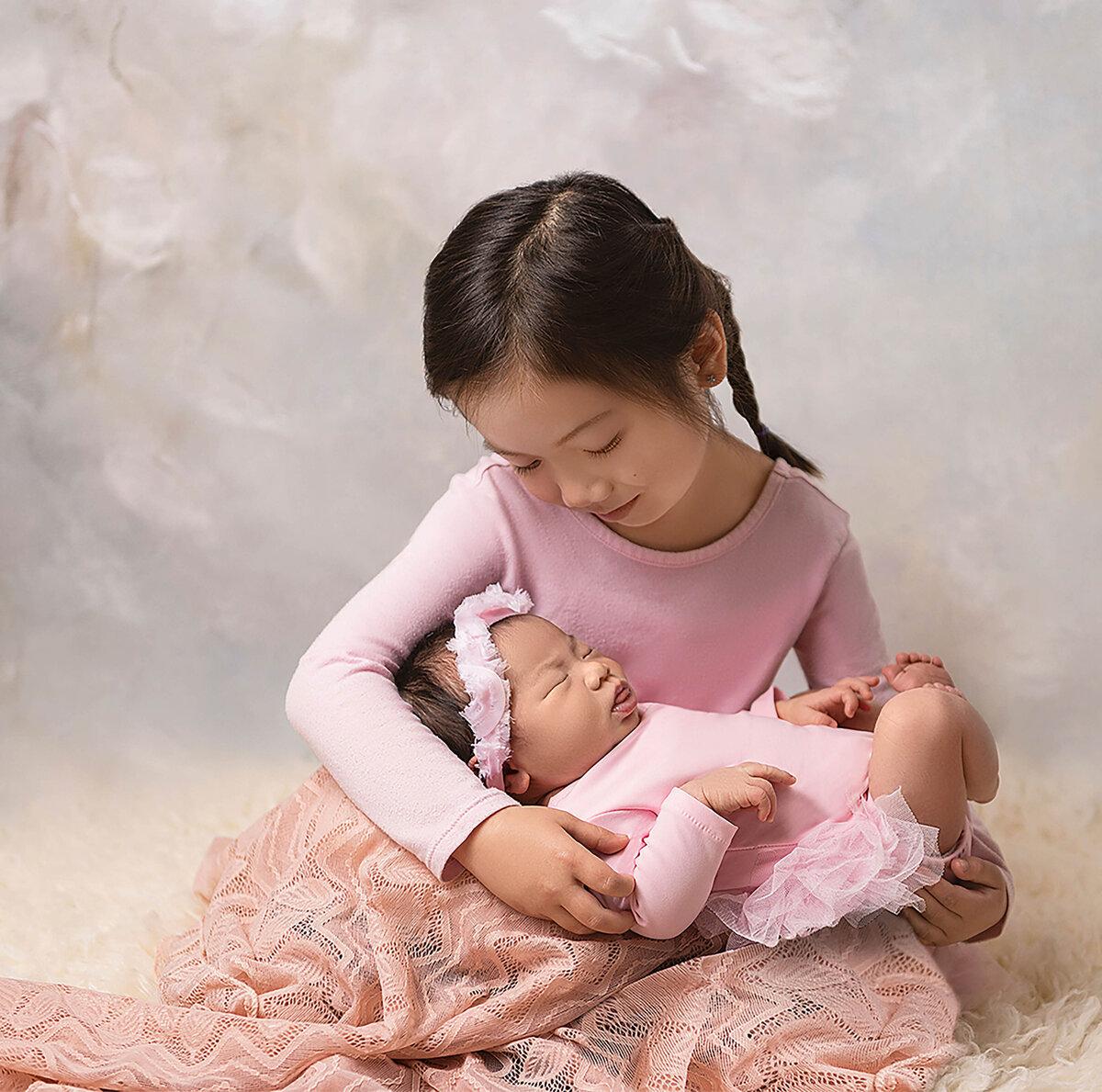 big sister gently holding newborn sister