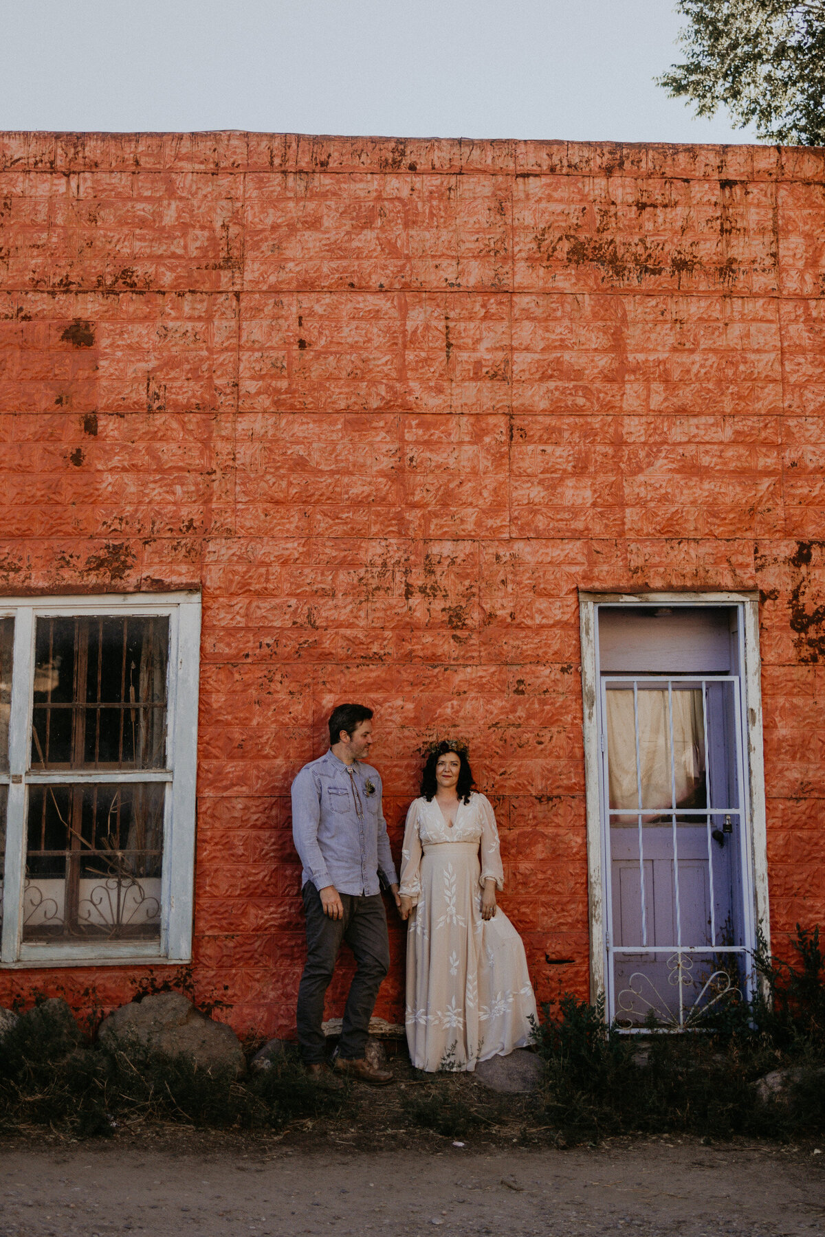 newlyweds standing together in front of a colorful wall in Taos