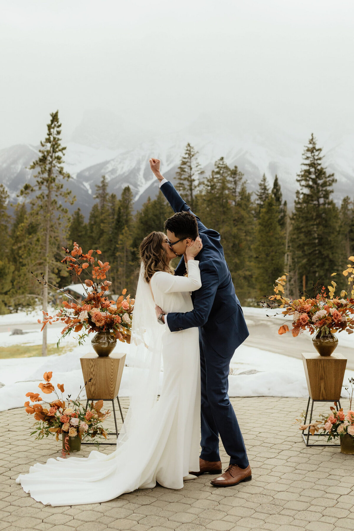 Couple kissing at wedding ceremony, stunning pink and tangerine florals, by Malorie Reiter Photography, adventurous and authentic wedding photographer in Lethbridge, Alberta. Featured on the Bronte Bride Vendor Guide.