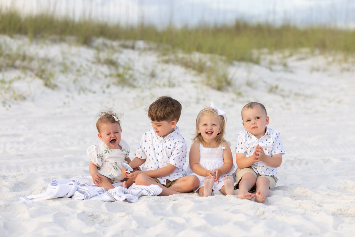 Four small kids sitting on a beach together